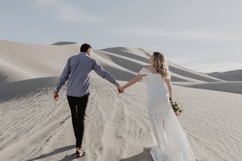 couple walking in desert nevada sand dunes in wedding attire by katherine krakowski photography a lake tahoe reno photographer