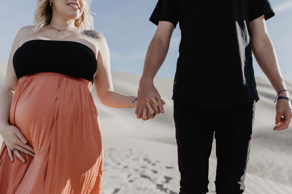 couple holding hands in desert during maternity session by katherine krakowski photography a lake tahoe reno photographer