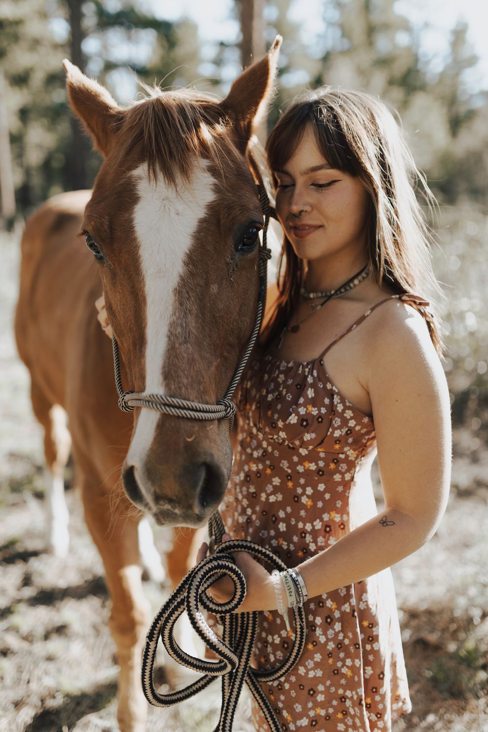 female holding horse in forest closing eyes during senior photo session wearing floral dress in reno nevada by katherine krakowski photographer