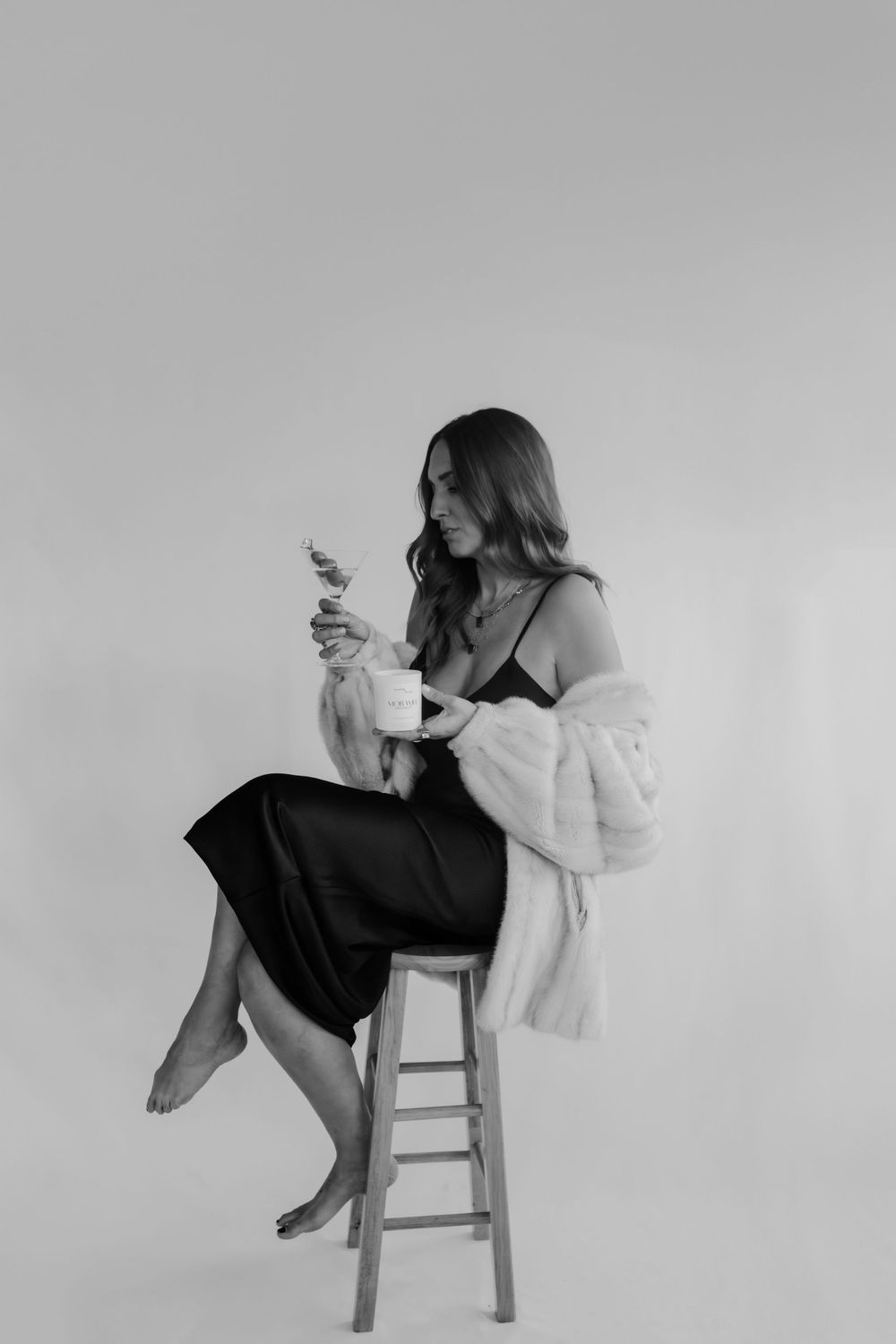 woman sitting on stool with mob wife mentality holding martini and candle in studio session by katherine krakowski lake tahoe reno photographer