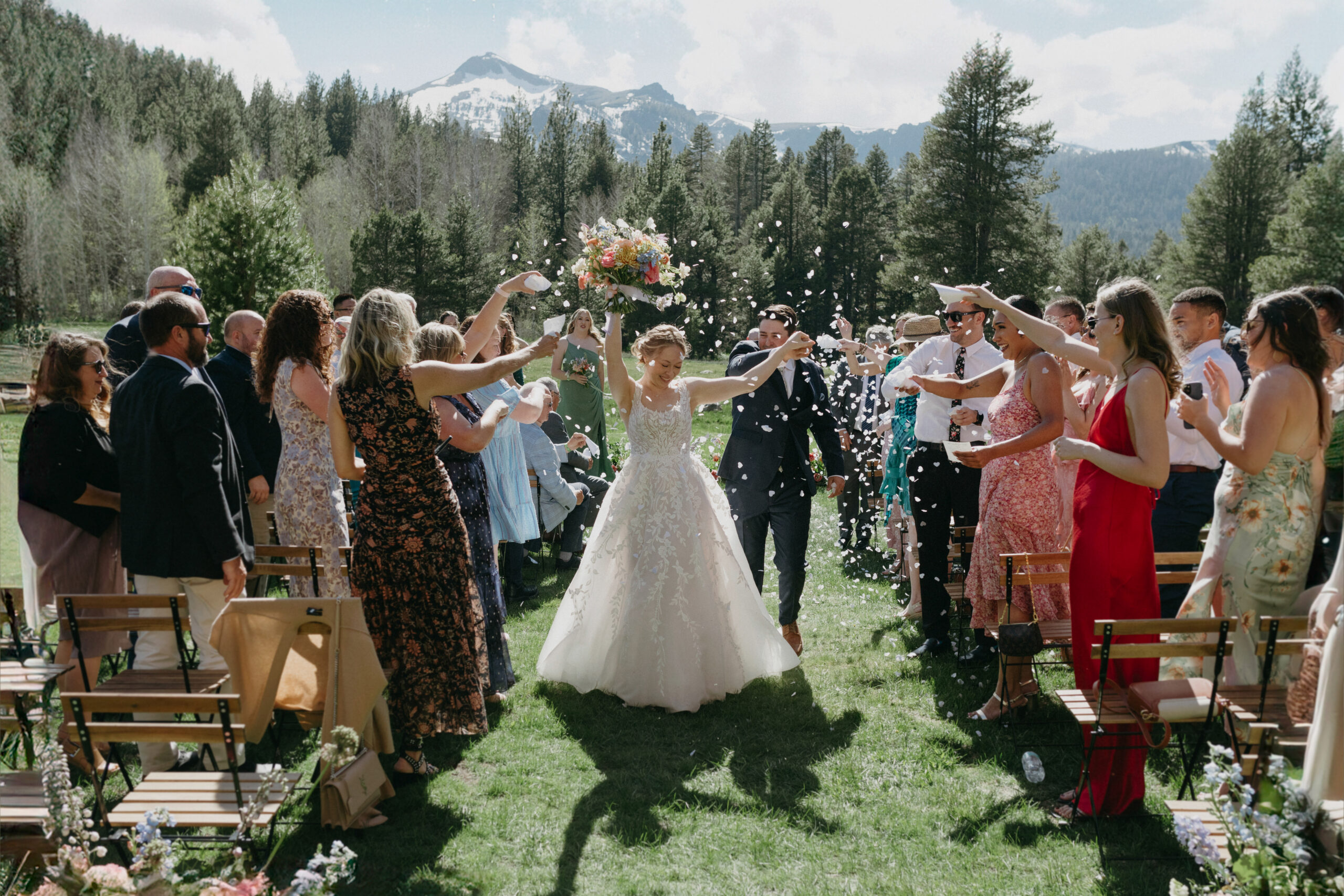 Bride and Groom in altar mountain background in Alpine County California being showered in white rose petals confetti.